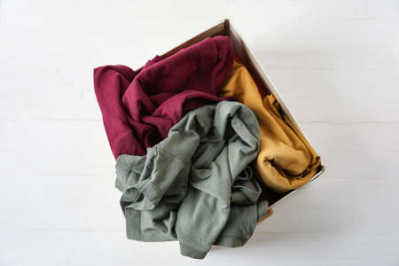Wardrobe box with clothes on white wooden background