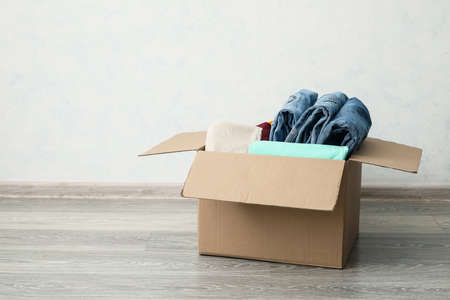 Wardrobe box with clothes near light wall