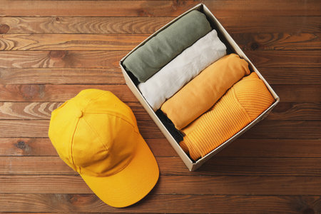 Wardrobe box with clothes and cap on wooden backgroundの写真素材