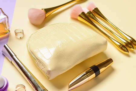 Stylish bag and decorative cosmetics on color background, closeup
