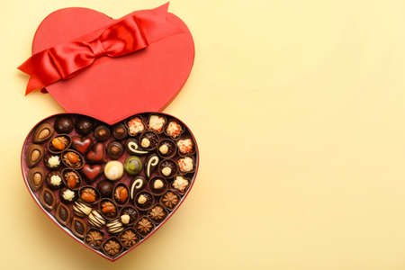 Heart-shaped box with chocolate candies on color backgroundの写真素材