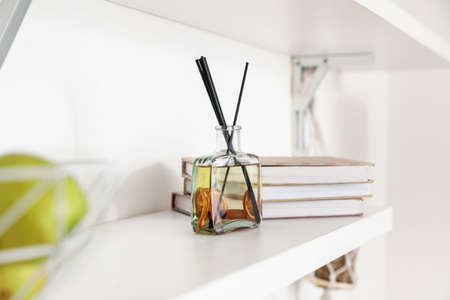 Aroma reed diffuser with books on shelf in room