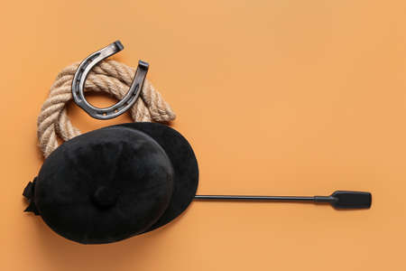 Horse riding helmet and crop with rope and horseshoe on color backgroundの写真素材