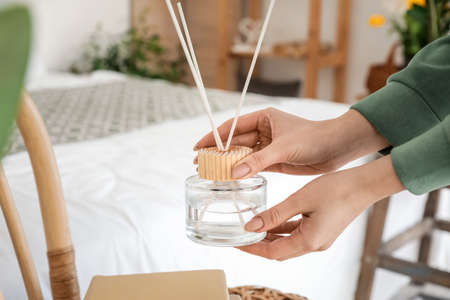 Woman with aroma reed diffuser at home