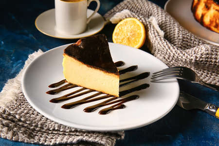 Plate with slice of tasty Basque burnt cheesecake on color background