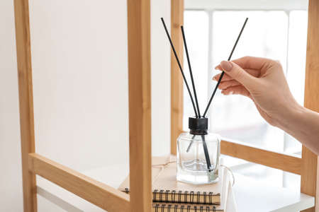 Woman with aroma reed diffuser at home