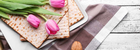 Jewish flatbread matza for Passover Seder and tulip flowers on wooden backgroundの写真素材