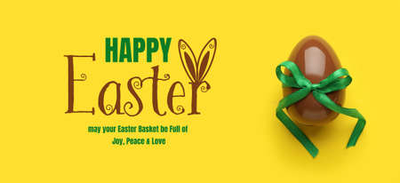 Tasty chocolate egg with ribbon on yellow background. happy easter celebration