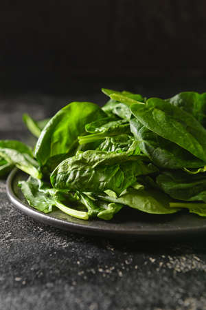 Plate with fresh spinach leaves on dark background, closeupの写真素材