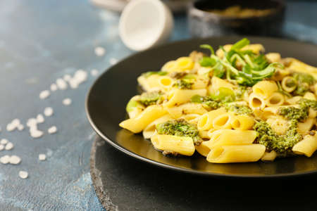 Plate with tasty pasta and pesto sauce on color background, closeup