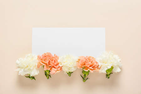 Beautiful carnation flowers and blank card on color backgroundの写真素材