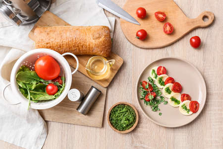 Plate with tasty caprese salad and ingredients on wooden backgroundの写真素材