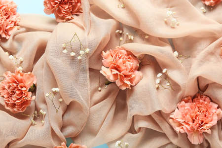 Beautiful carnation flowers and scarf on color background