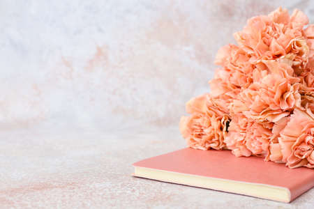 Beautiful carnation flowers and notebook on light backgroundの写真素材