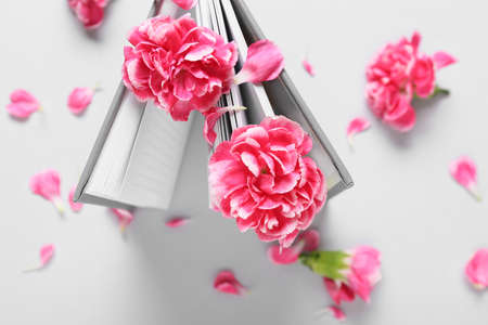 Beautiful carnation flowers and book on light backgroundの写真素材