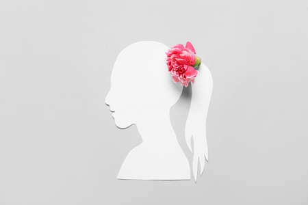 Paper female figure and beautiful carnation flower on color backgroundの写真素材