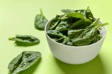 Bowl with fresh spinach leaves on color background, closeupの写真素材