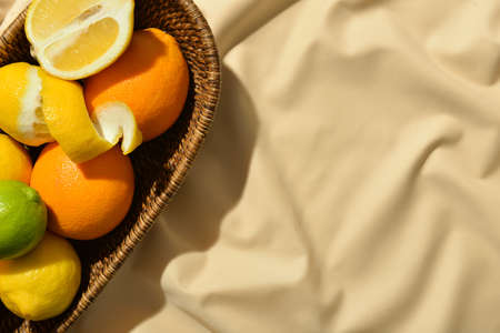 Wicker basket with healthy citrus fruits on light fabric backgroundの写真素材
