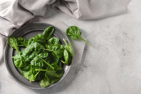Plate with fresh spinach leaves on light backgroundの写真素材