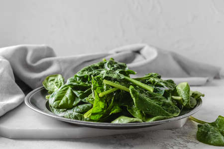 Plate with fresh spinach leaves on light backgroundの写真素材