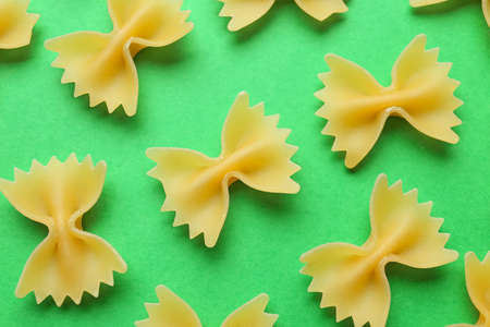Uncooked farfalle pasta on color background