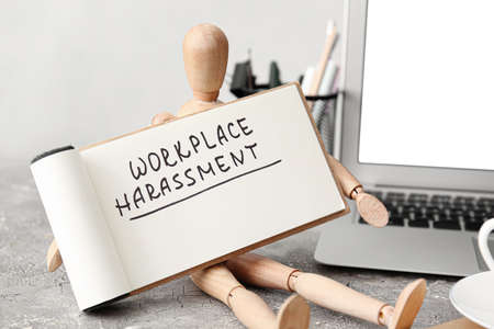Mannequin with text WORKPLACE HARASSMENT on tableの写真素材