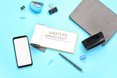 Stationery with text WORKPLACE HARASSMENT and mobile phone on color background
