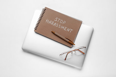 Notebook with text STOP HARASSMENT, laptop and eyeglasses on white backgroundの写真素材