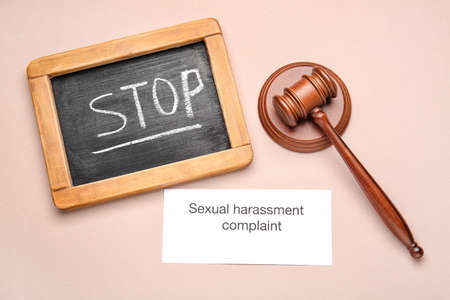 Text STOP SEXUAL HARASSMENT COMPLAINT with board and judge's gavel on color backgroundの写真素材