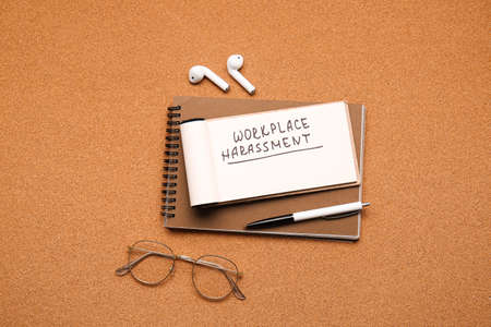 Notebooks with text WORKPLACE HARASSMENT, eyeglasses and earphones on color backgroundの写真素材