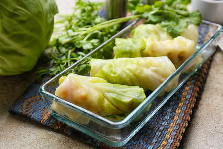 Baking dish with uncooked cabbage rolls on grunge background