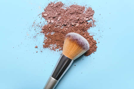 Makeup brush and loose eye shadow on color background