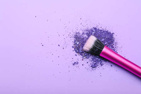 Makeup brush and loose eye shadow on color backgroundの写真素材