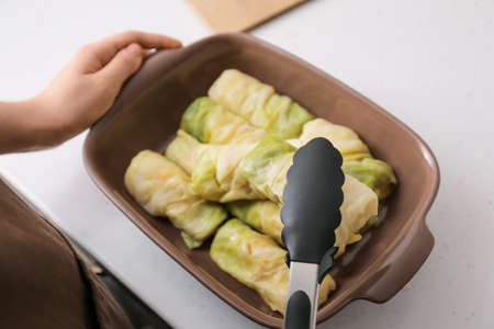 Woman preparing tasty stuffed cabbage rolls in kitchen, closeupの写真素材