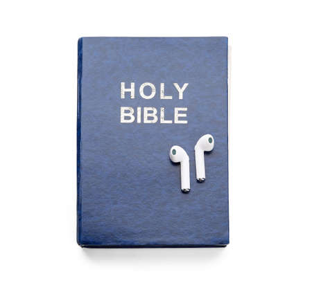 Holy Bible and earphones on white background