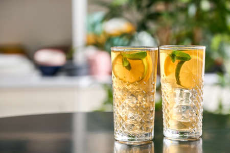 Glasses of tasty ice tea with lemon on table in room