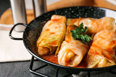Frying pan with tasty stuffed cabbage rolls on dark background, closeup