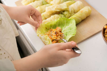 Woman preparing tasty stuffed cabbage rolls on table in kitchen, closeupの写真素材