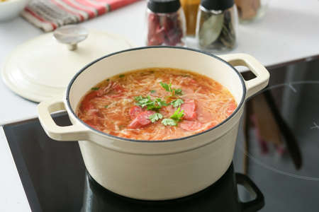 Cooking pot with tasty sauerkraut soup on electric stove in kitchen