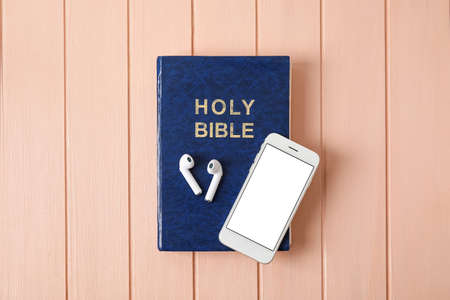 Holy Bible, earphones and mobile phone on color wooden backgroundの写真素材