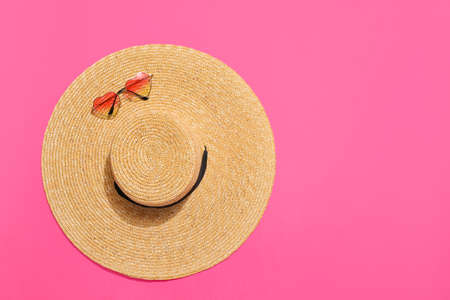 Stylish beach hat with sunglasses on color backgroundの写真素材