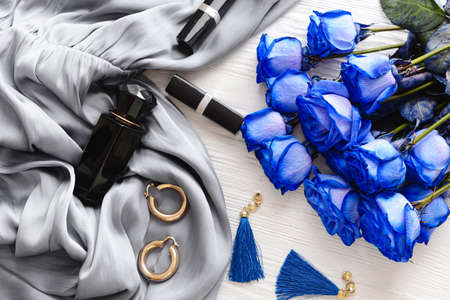 Beautiful blue roses, cosmetics and female accessories on white wooden backgroundの写真素材