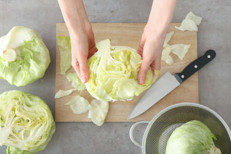 Female hands with iceberg lettuce on tableの写真素材