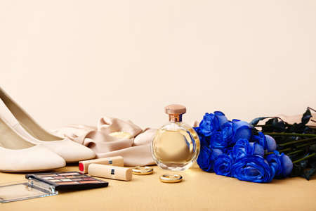 Beautiful blue roses, female accessories and cosmetics on color background