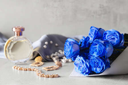 Beautiful blue roses, perfume and jewelry on light backgroundの写真素材