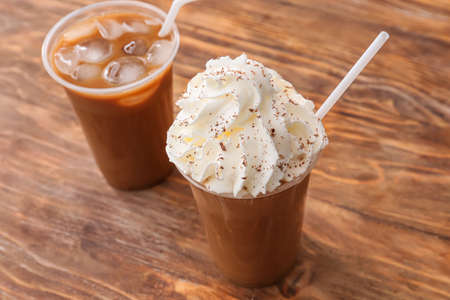 Glasses of tasty iced coffee with whipped cream on table