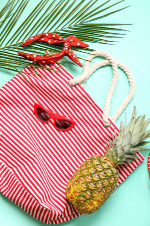 Stylish sunglasses, bag, headband and pineapple on color background, closeup