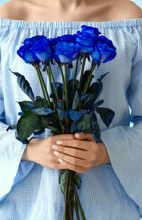 Woman with beautiful blue roses on color backgroundの写真素材