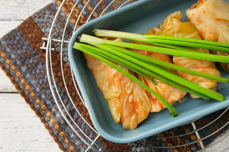 Baking dish with tasty stuffed cabbage rolls on light wooden background, closeupの写真素材