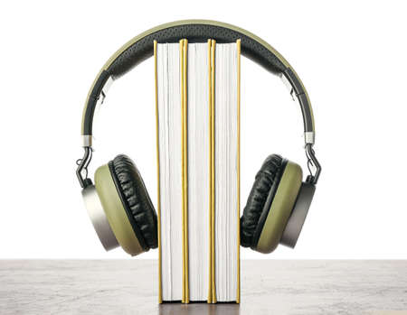 Modern headphones with books on table against white backgroundの写真素材